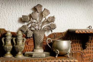 Süslü tuzluklar, lale duvarlı plaket ve Kolombiya evindeki beyaz desenli duvara karşı oyulmuş ahşap bir rafta aslan ayaklı gümüş bardak..