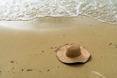 Hasır şapka, Covenhas 'ta sahil kenarındaki kumların üzerinde duruyor. Sessizlik ve tropikal dinginliği çağrıştırıyor. Açık kopya alanı ile birlikte.