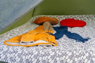 Kışlık palto, yastık ve tropikal ortamda desenli battaniyeyle dolu rahat bir kamp yeri..