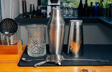 Barmenlik aletleri, karıştırıcı, süzgeç ve siyah hasırın üzerinde kaşık, ahşap tezgah.