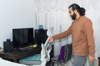 Ofis kurulumunda elinde kulaklıkla masaya bakan biri..