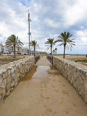 Yağmurlu havalarda iki tarafında palmiye ağaçları olan yaya köprüsünün geçidi manzarası.
