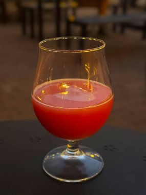 Yumuşak şehir ışıklarıyla aydınlatılan Kanlı Mary kokteylinin yakın çekimi dengesiz ve atmosferik kentsel bir ortam yaratıyor..