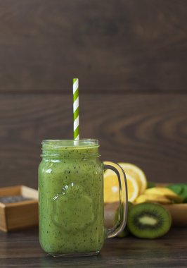 Kivi sağlıklı güler yüzlü. Kivi, ıspanak, muz, limon, chia tohum ile milkshake. Ahşap arka plan.