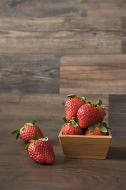 Ahşap arka plan üzerinde bir bambu kase taze çilek