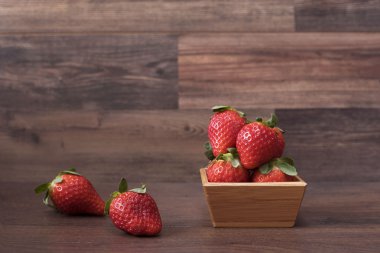 Ahşap arka plan üzerinde bir bambu kase taze çilek