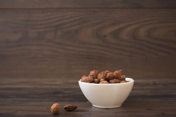 Caramelized almonds. Wood background. — Stock Photo, Image