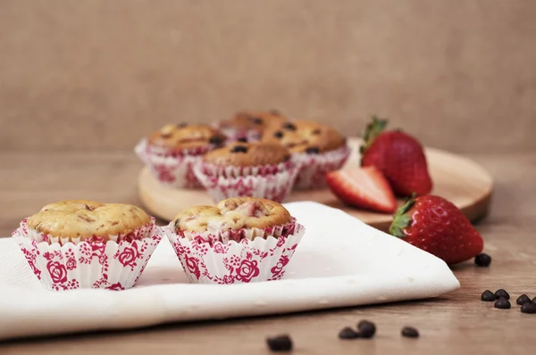 Strawberries and chocolate chip muffins on wooden background — Stock Photo, Image