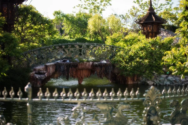 Beau pont sur le lac dans un parc verdoyant. Bel étang et passerelles entourés d'arbres et de fleurs. — Photo