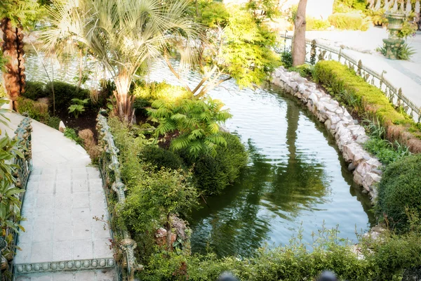 Hermoso puente sobre el lago en el parque verde. Hermoso estanque y pasarelas rodeadas de árboles y flores. —  Fotos de Stock