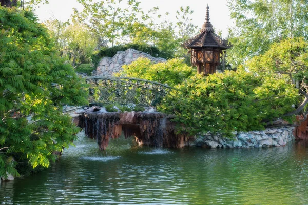 Schöne Brücke über den See im grünen Park. Schöne Teiche und Stege mit Bäumen und Blumen umgeben. — Stockfoto