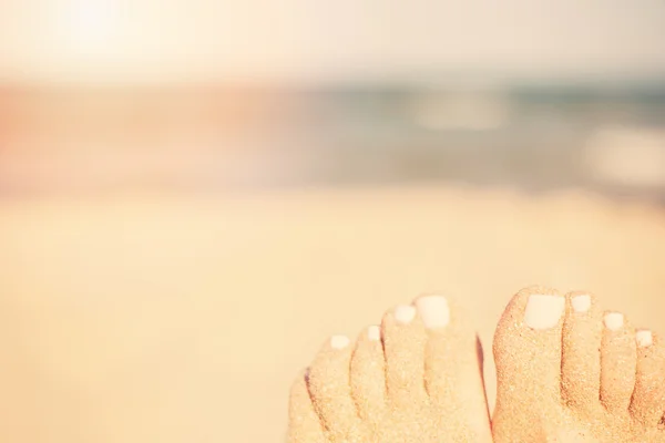 Concepto de vacaciones. Pies de mujer primer plano relajante en la playa, disfrutando del sol y espléndidas vistas. Pies de arena en la playa. Sol, sol neblina, resplandor — Foto de Stock