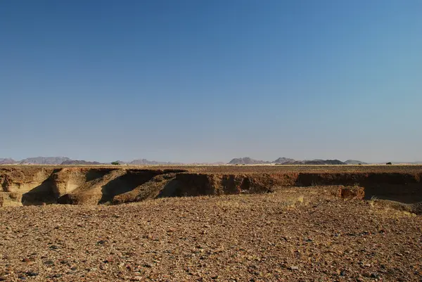 Πετρώδη έρημο αεροπλάνο σπασμένα από το φαράγγι και τα βουνά στο φόντο — Φωτογραφία Αρχείου