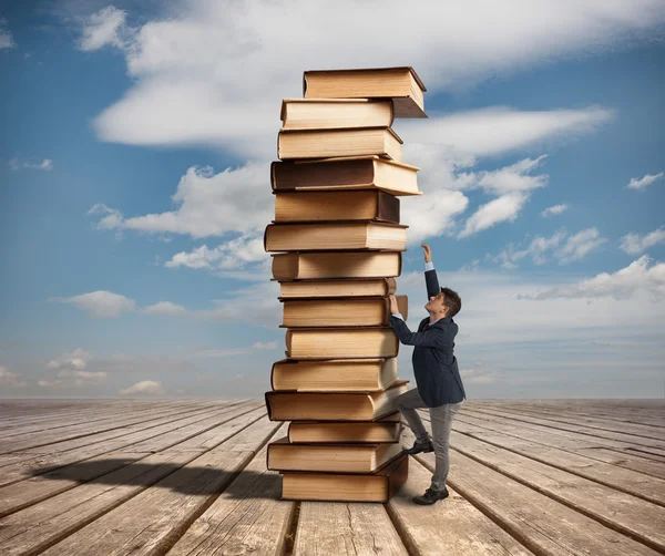 Homme grimpant une pile de livres — Photo