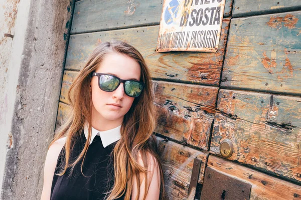 Girl in a sunglasses leaning on a wall — Stock Photo, Image