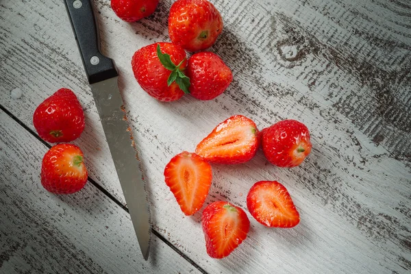Strawberries lying on a wooden table with a knife — Stock Photo, Image
