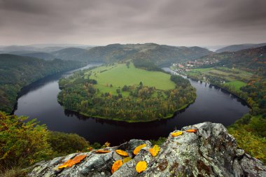 Vltava nehri, sonbahar yaprakları ile kara bulutlar