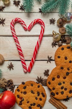 Noel arkaplanda ladin dalları, Noel oyuncakları, kurabiyeler, resmin solunda kalp şeklinde şekerler, hoş, yumuşak bir ışık. Tahta beyaz tahtalarda Noel arkaplanı