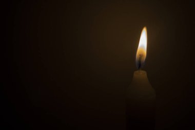 Karanlıkta beyaz bir mum. Ölülerin anıları. Kilise teması için arkaplan, kopyalama alanı olan dualar