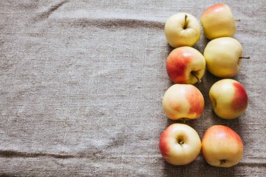 Rustic still life composition with apples in the right corner of the image on burlap fabrics with folds with copy space