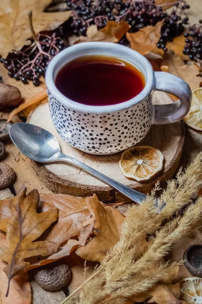 Sonbahar durgun yaşam kompozisyonu: sonbahar yaprakları ve elderberry ile ahşap standı üzerinde bir fincan çay