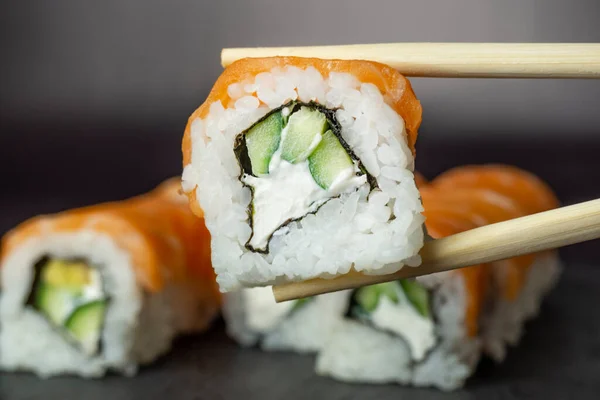 Siyah arka plandaki çubukta suşi. Geleneksel Japon yemeklerini kapatın.
