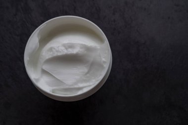 Siyah kapaklı beyaz kozmetik yüz kremi kavanozu açıldı.