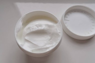 Siyah kapaklı beyaz kozmetik yüz kremi kavanozu açıldı.