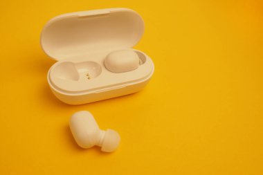 Telefon ve bilgisayar için bluetooth kulaklıklar. Fotokopi alanı olan sarı arka planda kablosuz kulaklıklar.