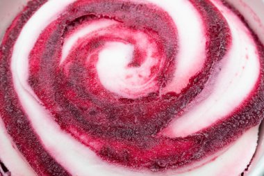 Yakın çekim soğuk beyaz dondurma ve bir kova doldurma. Çilekli, ahududu reçelli, sarmal şekilli donmuş bir tatlının en üst görüntüsü.