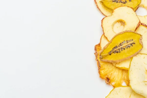 Üst görünüm meyve cipsleri (elmalar, ananas ve kivi) beyaz arka planda bulunur. Kurumuş meyvelerin en üst görüntüsü. Sağlıklı yeme kavramı