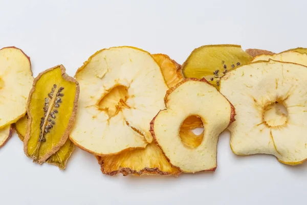 Üst görünüm meyve cipsleri (elmalar, ananas ve kivi) beyaz arka planda bulunur. Kurumuş meyvelerin en üst görüntüsü. Sağlıklı yeme kavramı