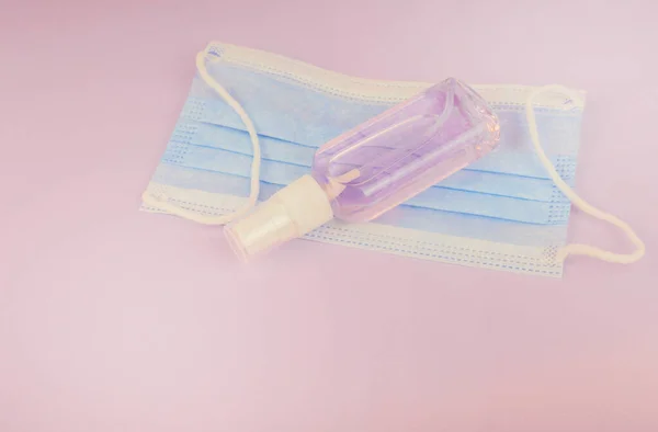 Dezenfeksiyon için antiseptik spreyi, mavi misk kokulu pembe bir arka planda el dezenfektanı şişesi. Mesaj için boşluk kopyala. Temizleyici ürün. Beyaz ışıkla tıp ve kozmetoloji teması üzerine arka plan