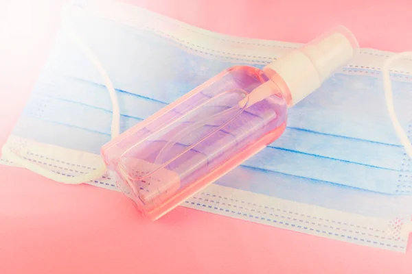 Dezenfeksiyon için antiseptik spreyi, pembe arka planda el dezenfektanı şişesi ve mavi misk kokusu. Mesaj için boşluk kopyala. Temizleyici ürün. Güneş ışığıyla tıp ve kozmetoloji teması üzerine geçmiş