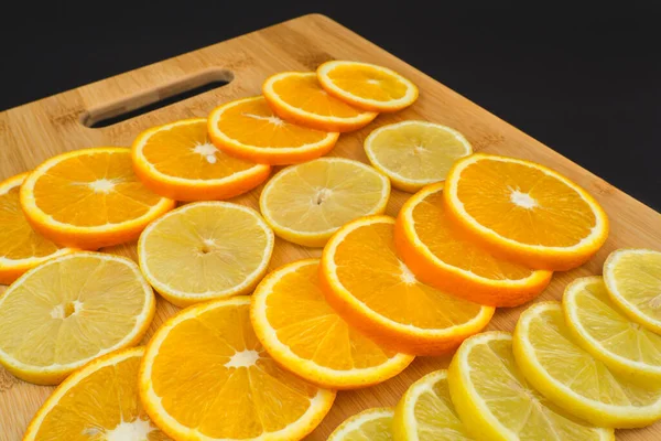 Tahtada limon ve portakal dilimleri. Siyah arkaplanda meyvelerin yakın plan görüntüsü