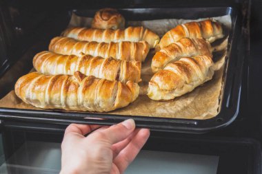 Hamurdaki sosisleri fırın tepsisine koy. Kadın eliyle parşömen üzerinde pişirme