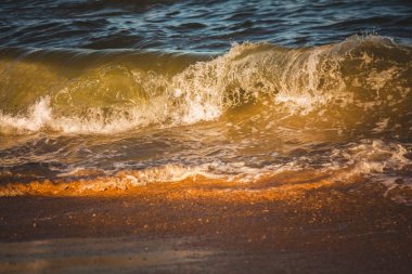 Sahilde sıcak renklerde deniz ya da okyanus dalgaları. Denizin gücü. Aile, romantik tatil, yaz havası, seyahat.