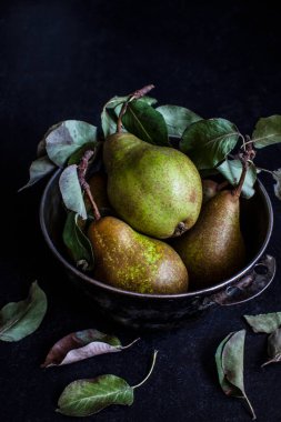 Siyah arka planda metal bir kasedeki yeşil armutların yaşam bileşimi. Estetik meyve, koyu arkaplan. Kırsal biçim