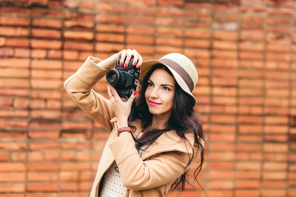 Cute one girl photographer on a background of a brick wall — Stock Photo, Image