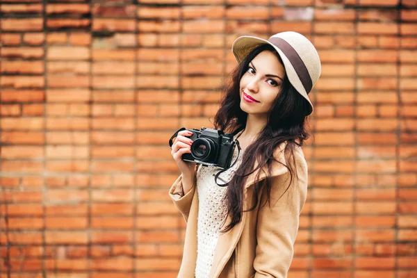 Симпатичная девушка фотограф на фоне кирпича — стоковое фото