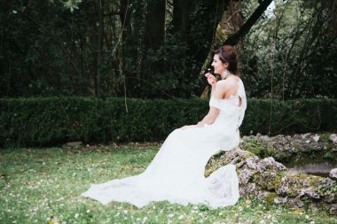 gizli bir bahçe içinde gülümseyen güzel genç gelin