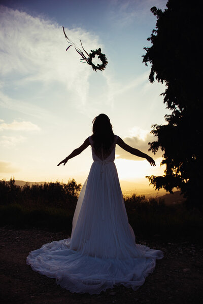 Silhouette of bride in a landscape, with a flower crown in air