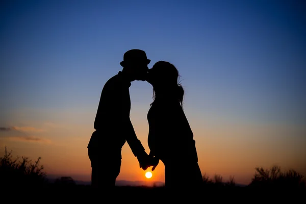 Sziluettjét egy pár a naplemente, a csók, a szülési — Stock Fotó