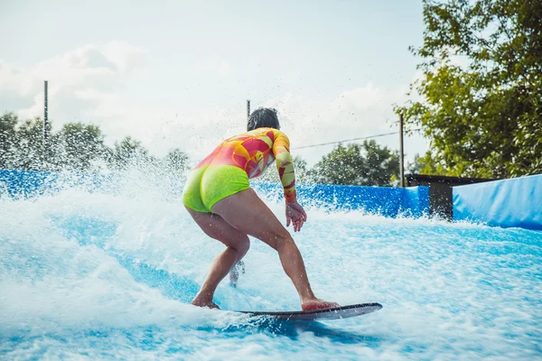 Güzel genç kadın bir mayo yapay dalga surfboard ile