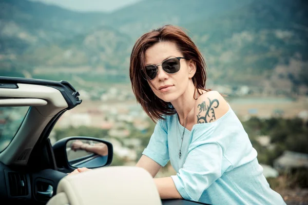Cabrio tuşları ile elinde duran güneş gözlüklü genç güzel kadın