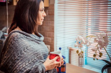 Güzel genç kadın kahve geç pencereden dışarı bakarak içme