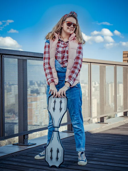Het meisje op een zonnige dag voorzien van een skateboard in zijn hand Rechtenvrije Stockafbeeldingen