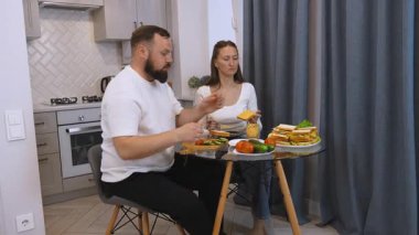 Bir adam ve bir kadın, karı koca, modern bir mutfakta sağlıklı malzemelerden burbros pişiriyorlar. Evde birbirine aşık bir çiftle yemek pişirmek..