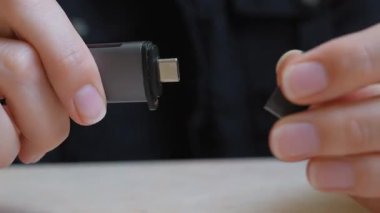 Modern bir USB-C flash belleği dikkatlice açıp kapatan kadın elleri. Veri depolama, bilgi güvenliği, dijital bağlantı ve modern elektronik teknoloji kavramı