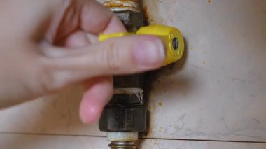 Kadın el, evdeki doğal gaz akışını kesmek, güvenliği sağlamak ve potansiyel sızıntı ve kazaları önlemek için ana gaz boru hattının sarı kolunu kapatıyor.